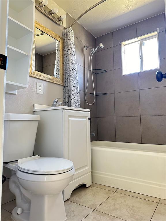 bathroom with tile patterned flooring, shower / bath combination with curtain, and toilet