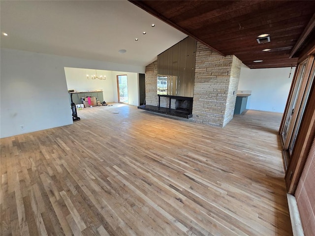 unfurnished living room featuring an inviting chandelier, light wood-style flooring, a multi sided fireplace, and high vaulted ceiling