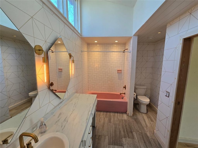 full bath with wood finished floors, toilet, tile walls, and shower / washtub combination