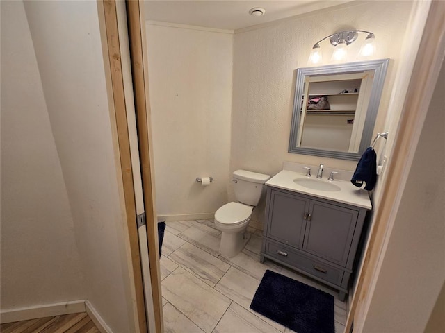 bathroom featuring toilet, vanity, and baseboards