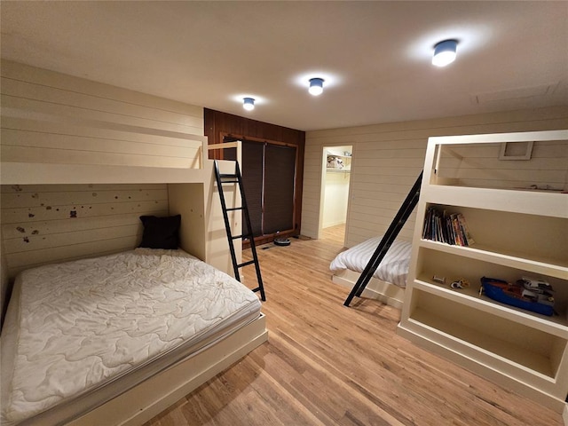 bedroom featuring wooden walls and light wood-type flooring