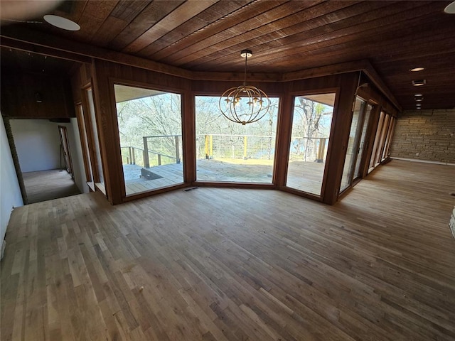 unfurnished dining area featuring wood finished floors, wood ceiling, a wealth of natural light, and a chandelier