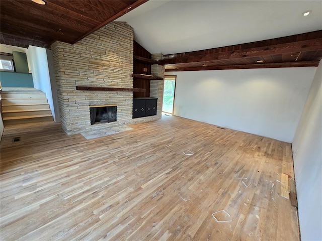 unfurnished living room featuring stairs, vaulted ceiling with beams, wood finished floors, and a fireplace