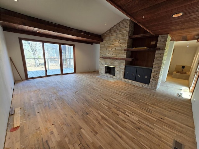 unfurnished living room with visible vents, lofted ceiling with beams, wood-type flooring, a stone fireplace, and wood ceiling