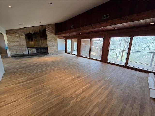 unfurnished living room with visible vents, wood-type flooring, high vaulted ceiling, and a fireplace