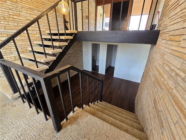 stairs featuring a towering ceiling and wood finished floors