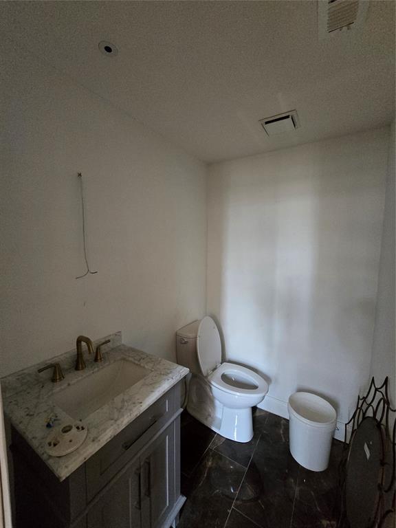 half bath featuring visible vents, toilet, and vanity