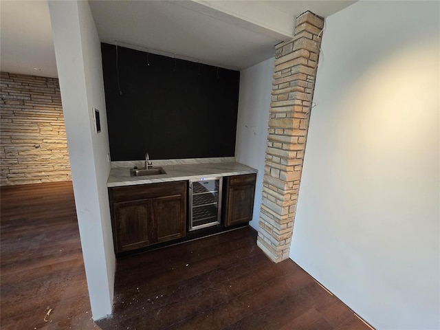 bar featuring wet bar, decorative columns, a sink, dark wood-type flooring, and wine cooler