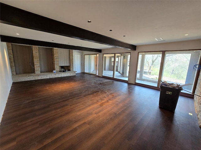 unfurnished living room with dark wood finished floors, beam ceiling, a brick fireplace, and recessed lighting