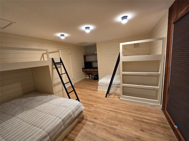 801 NE Ave C, Idabel, OK 74745 - bedroom featuring light wood-style floors and wooden walls