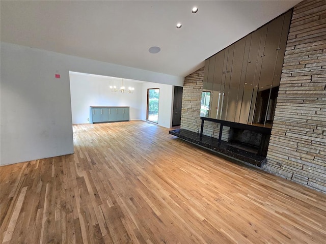 801 NE Ave C, Idabel, OK 74745 - unfurnished living room with a chandelier, light wood-style flooring, high vaulted ceiling, a fireplace, and recessed lighting