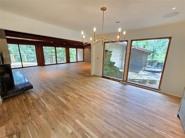 801 NE Ave C, Idabel, OK 74745 - unfurnished living room featuring a chandelier, light wood-type flooring, and healthy amount of natural light