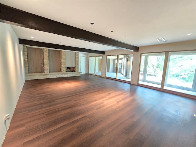 801 NE Ave C, Idabel, OK 74745 - unfurnished living room featuring beam ceiling, dark wood-style floors, a brick fireplace, and recessed lighting