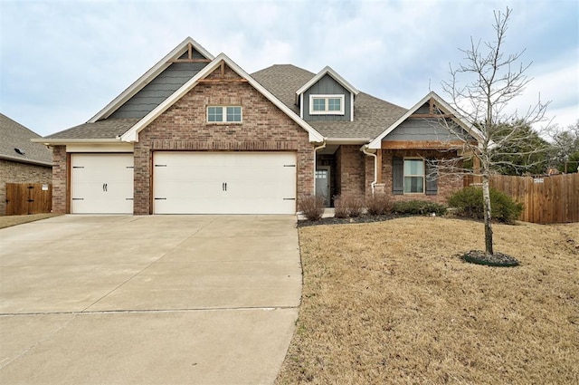 craftsman-style home with fence, brick siding, driveway, and roof with shingles