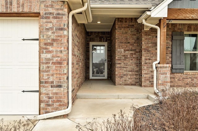 doorway to property featuring brick siding and a garage