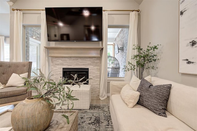 living area with a stone fireplace and wood finished floors