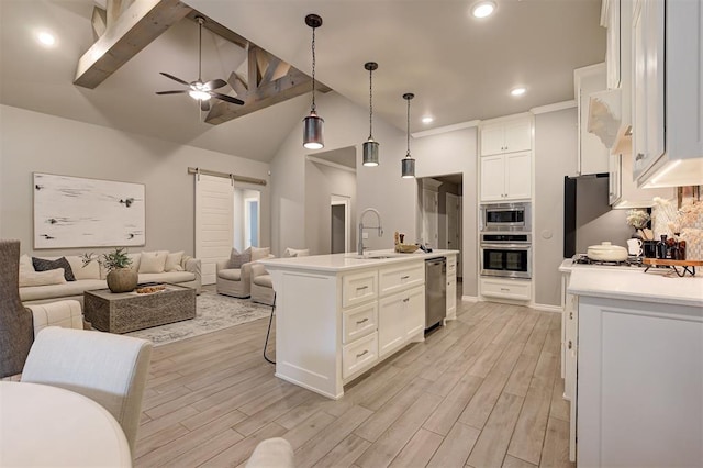 kitchen featuring a barn door, open floor plan, appliances with stainless steel finishes, and a sink