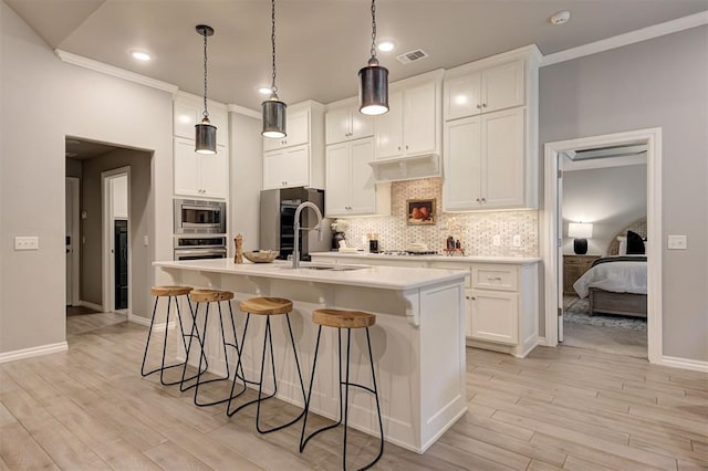 kitchen with stainless steel microwave, visible vents, decorative backsplash, a kitchen breakfast bar, and a sink