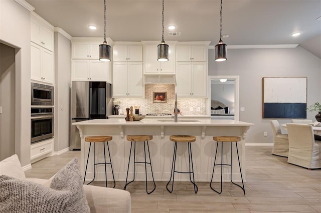 kitchen with a sink, stainless steel appliances, a kitchen bar, open floor plan, and backsplash