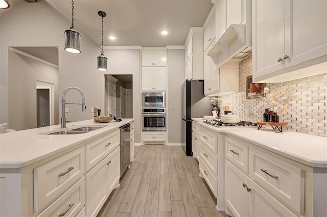 kitchen with tasteful backsplash, light countertops, light wood-style floors, stainless steel appliances, and a sink