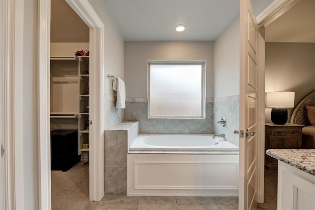 bathroom with a walk in closet and a bath