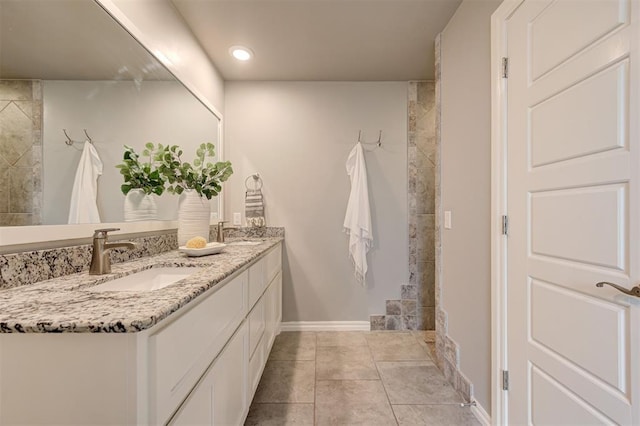 bathroom featuring a sink, baseboards, double vanity, and tile patterned floors