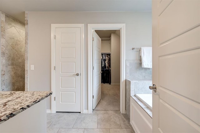 full bathroom with baseboards, a garden tub, tile patterned flooring, and a tile shower