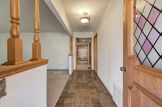 entryway with dark colored carpet, visible vents, baseboards, and a textured ceiling