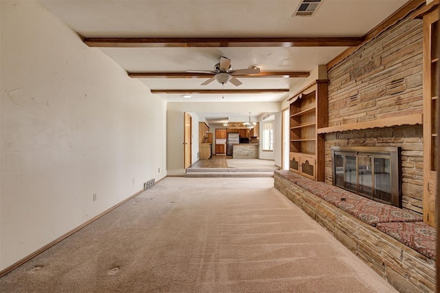 unfurnished living room featuring a ceiling fan, baseboards, visible vents, a fireplace, and beamed ceiling