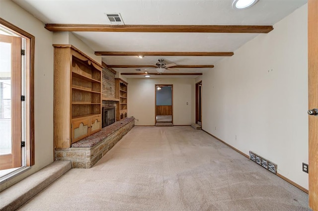 unfurnished living room with a glass covered fireplace, beam ceiling, baseboards, and visible vents