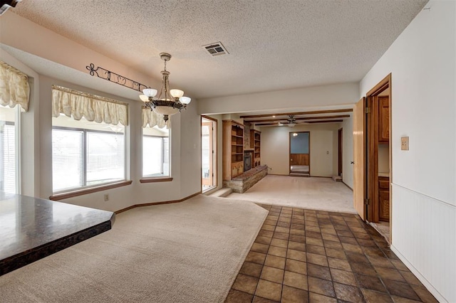 unfurnished dining area featuring a wainscoted wall, carpet flooring, a textured ceiling, and visible vents