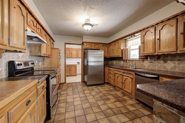 kitchen featuring visible vents, a sink, under cabinet range hood, appliances with stainless steel finishes, and dark countertops