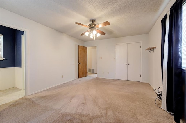 unfurnished bedroom featuring visible vents, a textured ceiling, connected bathroom, light colored carpet, and ceiling fan