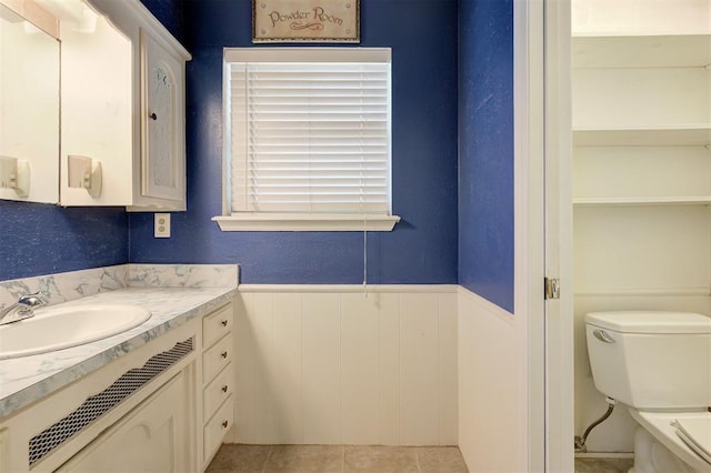 bathroom with vanity, tile patterned floors, toilet, and a wainscoted wall