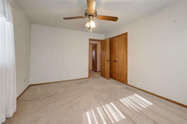 empty room featuring light carpet, ceiling fan, and baseboards