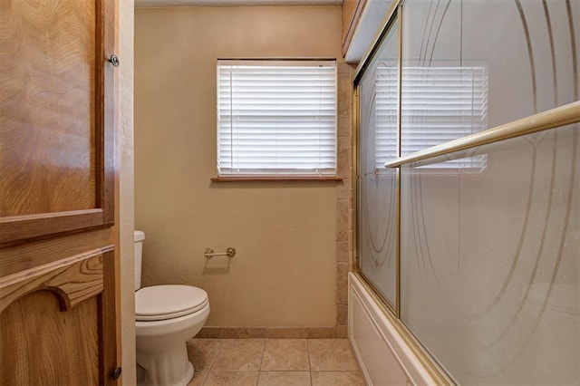 full bath with tile patterned floors, baseboards, toilet, and shower / bath combination with glass door