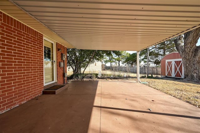 view of patio with an attached carport, an outbuilding, fence, and a storage shed