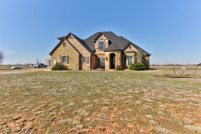 french country home featuring stone siding and a front lawn