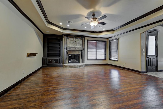 unfurnished living room with a tray ceiling, wood finished floors, visible vents, and ceiling fan