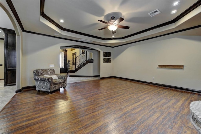 sitting room featuring visible vents, ceiling fan, baseboards, a tray ceiling, and arched walkways