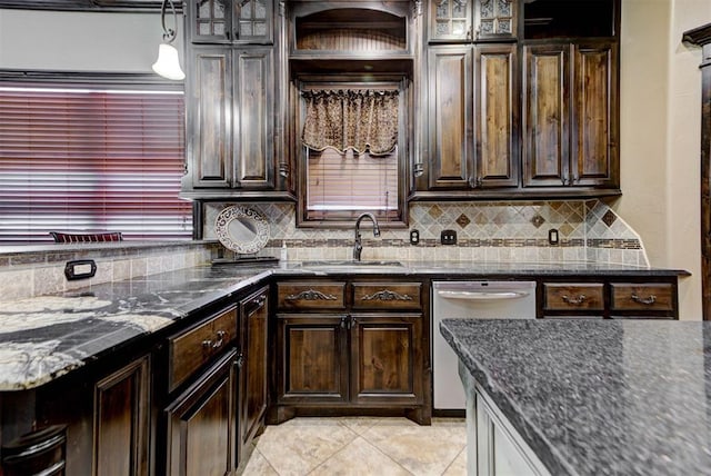 kitchen with a sink, backsplash, stainless steel dishwasher, and dark stone counters