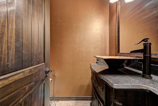 bathroom with tile patterned flooring, a textured wall, and baseboards