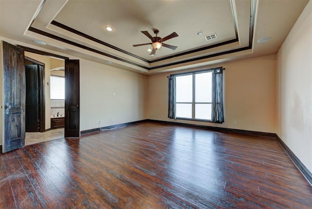 unfurnished room featuring visible vents, a raised ceiling, hardwood / wood-style floors, and a ceiling fan