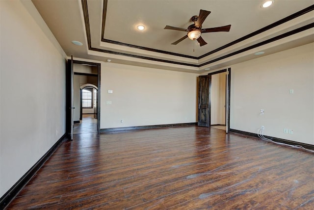 unfurnished room featuring ceiling fan, baseboards, a tray ceiling, and dark wood-style flooring