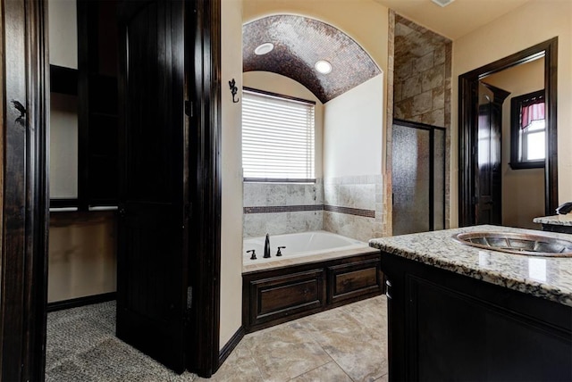 full bathroom featuring vanity, a bath, a stall shower, and a wealth of natural light