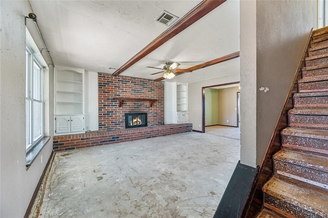 unfurnished living room with visible vents, built in shelves, stairway, and a brick fireplace