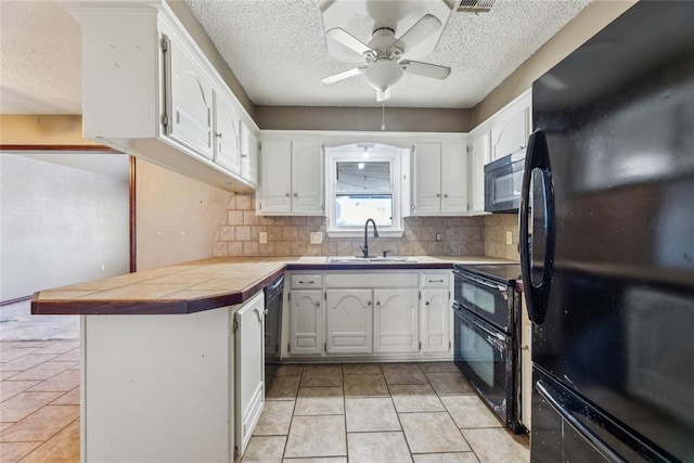 kitchen featuring black appliances, light tile patterned floors, a peninsula, white cabinetry, and a sink