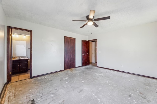 unfurnished bedroom with a textured ceiling, ensuite bathroom, baseboards, and a ceiling fan