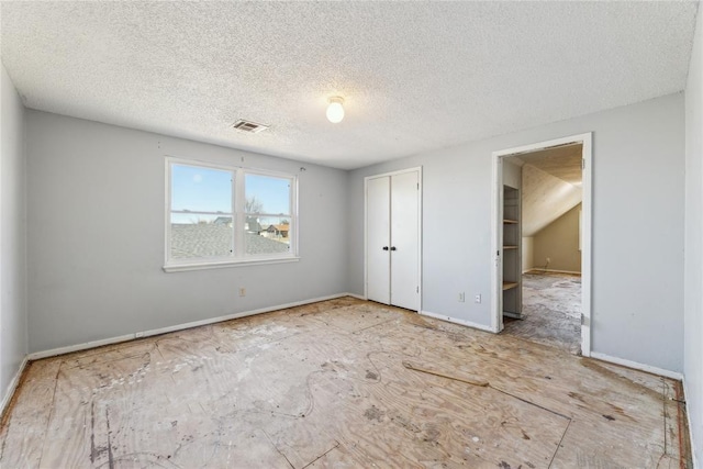 unfurnished bedroom featuring visible vents, baseboards, a textured ceiling, and a closet