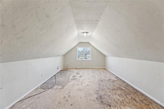 bonus room featuring vaulted ceiling, baseboards, and a textured ceiling